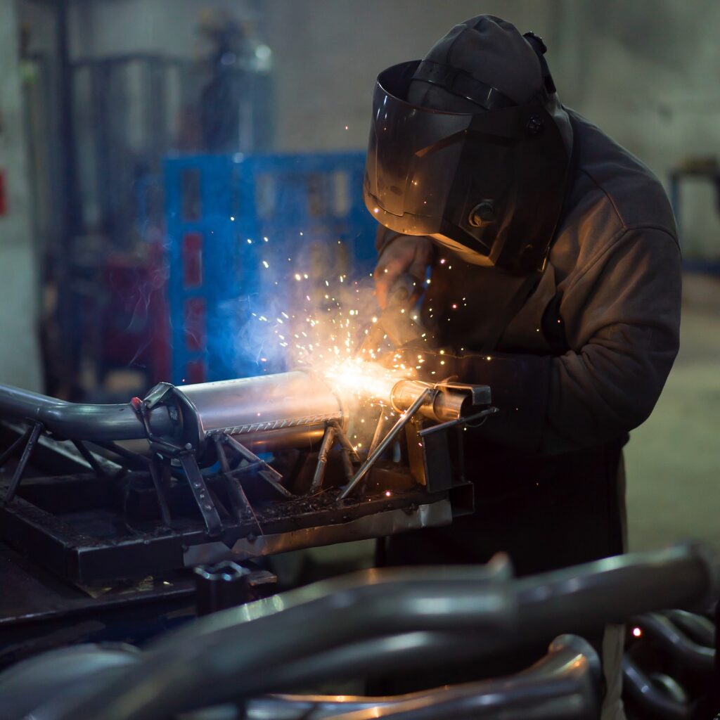 worker welding exhaust pipes pieces together